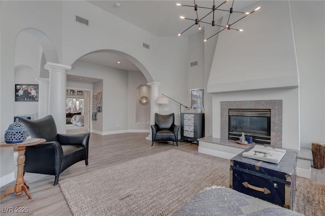 4594 Blue Mesa Way, Las Vegas, NV 89129 - living area featuring decorative columns, visible vents, a high end fireplace, arched walkways, and wood finished floors