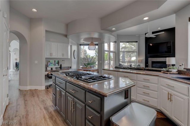 4594 Blue Mesa Way, Las Vegas, NV 89129 - kitchen with a ceiling fan, a center island, arched walkways, white cabinets, and black gas stovetop