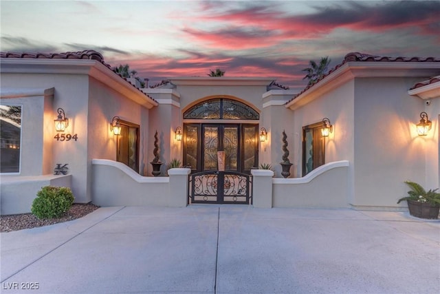 4594 Blue Mesa Way, Las Vegas, NV 89129 - exterior entry at dusk featuring a gate, stucco siding, french doors, and a tile roof