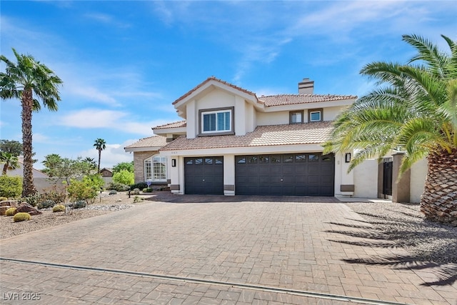 view of front of property with an attached garage, stucco siding, a tile roof, and a chimney