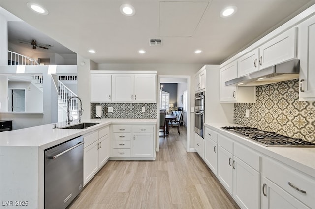 kitchen with visible vents, light countertops, under cabinet range hood, a sink, and appliances with stainless steel finishes