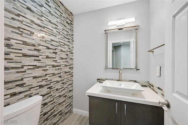 bathroom with toilet, tile walls, wood finished floors, and vanity