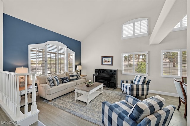 living room with high vaulted ceiling, baseboards, and light wood-type flooring
