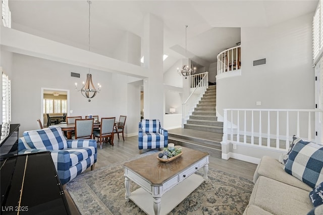 living room featuring an inviting chandelier, a towering ceiling, and wood finished floors
