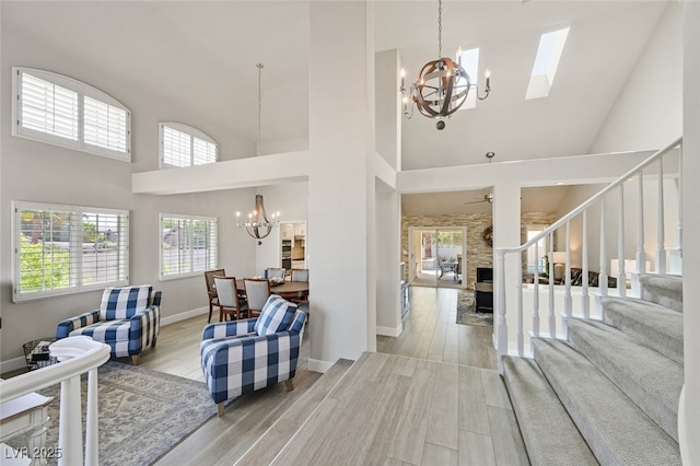 entryway with baseboards, high vaulted ceiling, stairway, light wood finished floors, and a notable chandelier