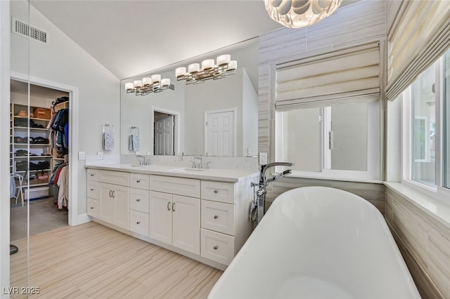 full bath with visible vents, a notable chandelier, a sink, and lofted ceiling
