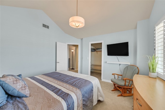 bedroom with light colored carpet, vaulted ceiling, a spacious closet, and visible vents