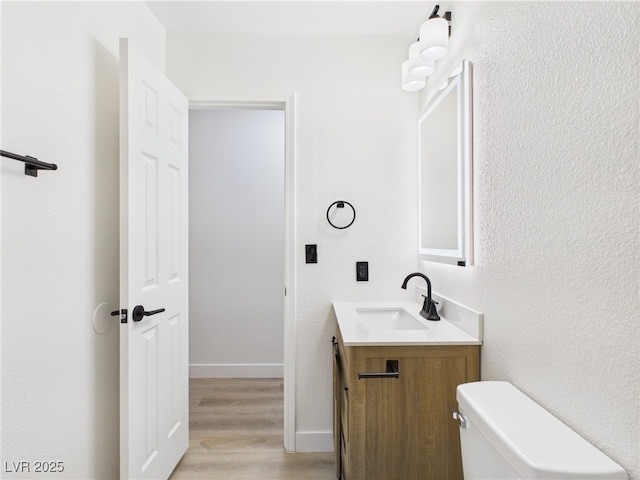 bathroom featuring vanity, baseboards, toilet, and wood finished floors