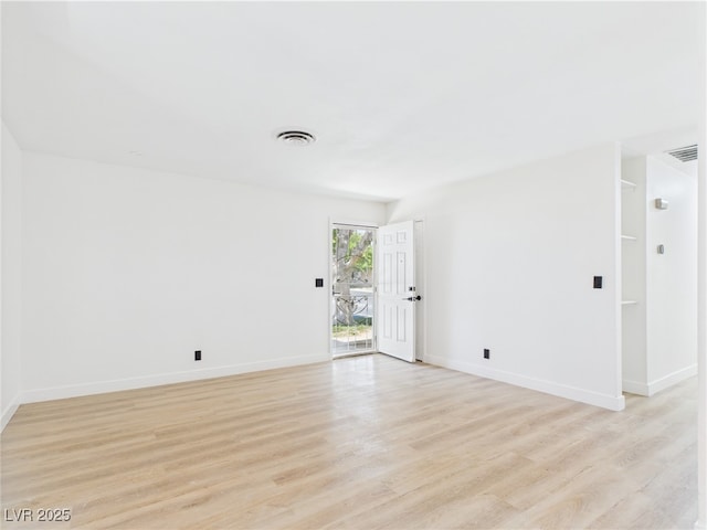 spare room featuring baseboards, light wood finished floors, and visible vents