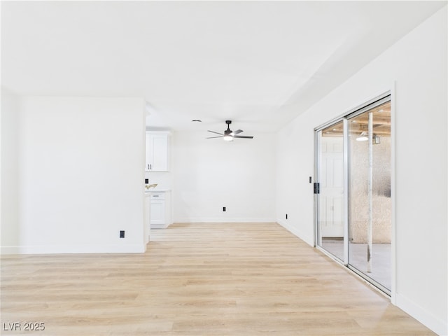 spare room featuring baseboards, a ceiling fan, and light wood-style flooring