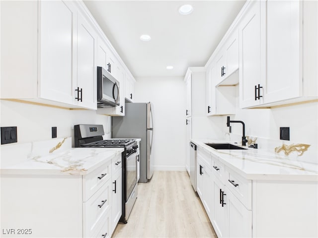 kitchen featuring light wood-style floors, recessed lighting, white cabinets, a sink, and appliances with stainless steel finishes