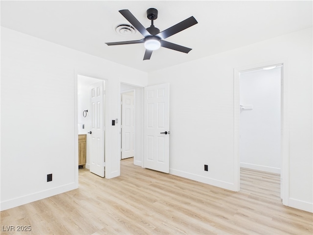 unfurnished bedroom with baseboards, light wood-style flooring, and a walk in closet