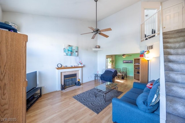 living room featuring ceiling fan, stairs, wood finished floors, and visible vents