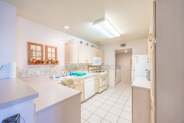 kitchen featuring visible vents, a peninsula, white appliances, light countertops, and light tile patterned floors