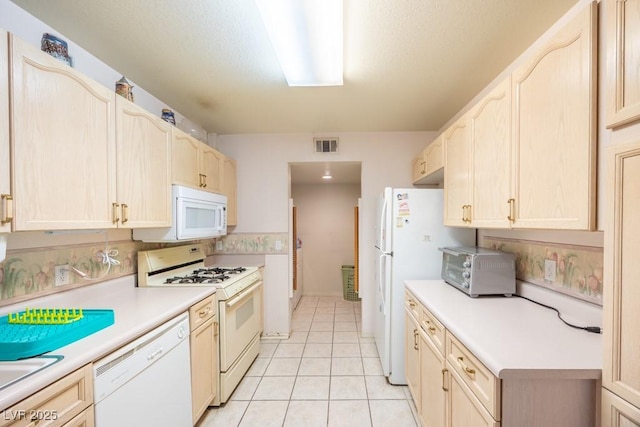 kitchen with light brown cabinetry, white appliances, light countertops, light tile patterned floors, and visible vents