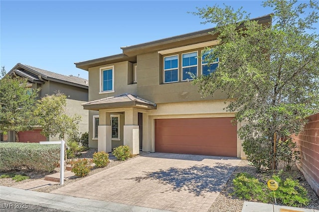view of front of property with a garage, decorative driveway, stucco siding, and fence