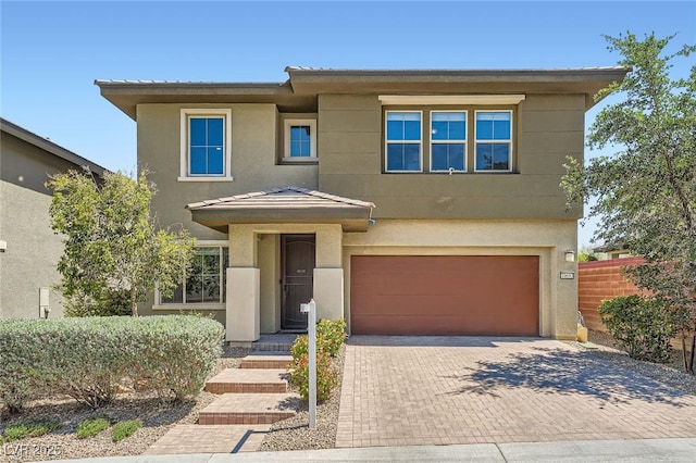view of front facade featuring a garage, fence, stucco siding, and decorative driveway