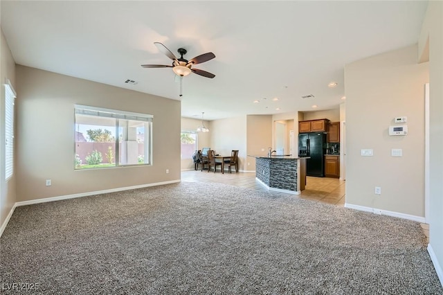 living area with baseboards, visible vents, ceiling fan with notable chandelier, and light colored carpet
