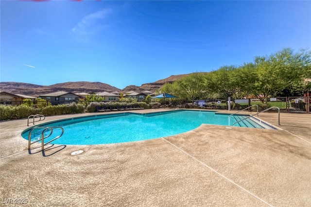 community pool featuring fence, a mountain view, and a patio area