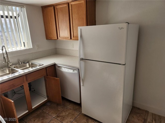 kitchen featuring a sink, brown cabinets, a healthy amount of sunlight, and white appliances