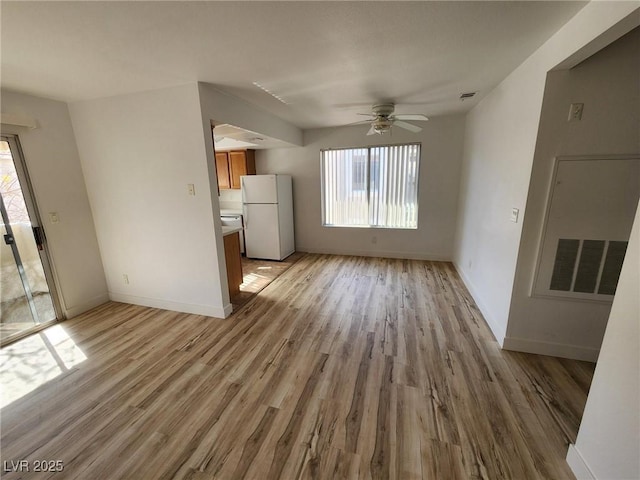 unfurnished living room with light wood-style floors, baseboards, ceiling fan, and visible vents