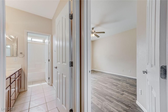full bath with vanity, wood finished floors, baseboards, a tub, and a ceiling fan