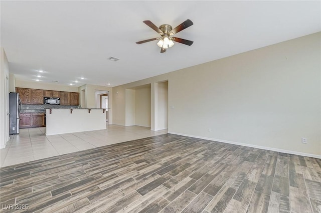 unfurnished living room with ceiling fan, visible vents, baseboards, light wood finished floors, and recessed lighting