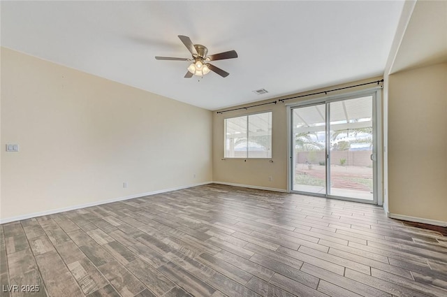 empty room with baseboards, ceiling fan, wood finished floors, and visible vents