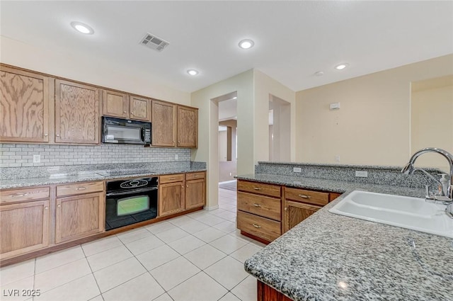 kitchen with visible vents, decorative backsplash, a sink, light tile patterned floors, and black appliances