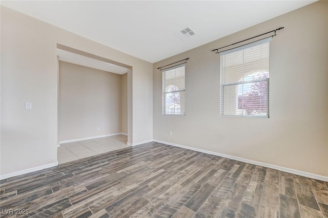unfurnished room featuring baseboards, visible vents, and wood finished floors