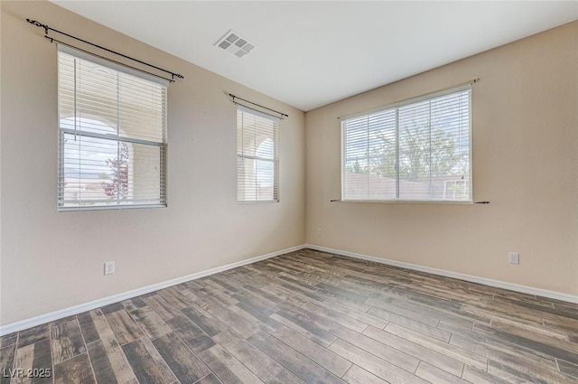 unfurnished room featuring baseboards, wood finished floors, and visible vents