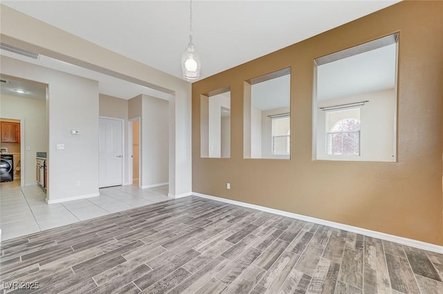 unfurnished room featuring washer / clothes dryer, baseboards, visible vents, and light wood finished floors