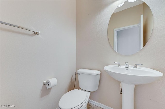 half bath featuring toilet and a sink