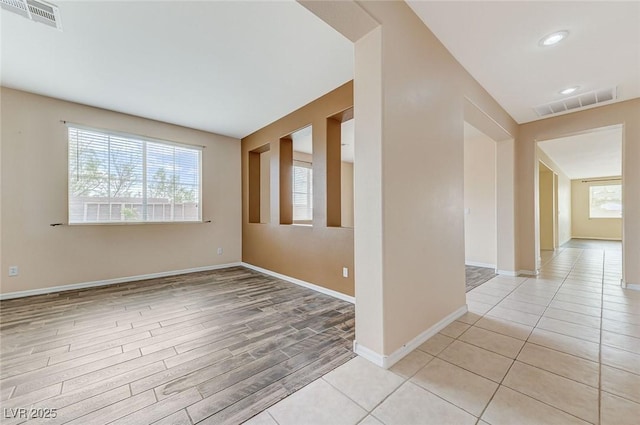 empty room featuring a wealth of natural light, light wood-style flooring, and visible vents