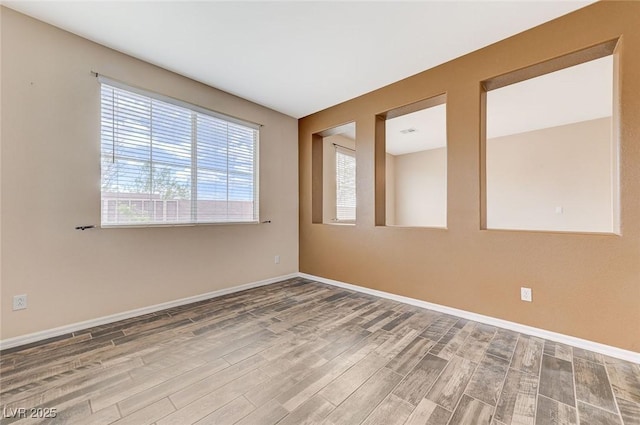 unfurnished room with baseboards and wood finished floors