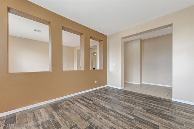 unfurnished room featuring baseboards, visible vents, and wood tiled floor