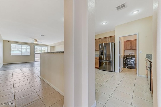 corridor featuring washer / dryer, light tile patterned floors, baseboards, and visible vents