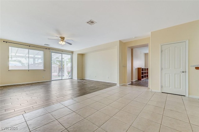 spare room with baseboards, ceiling fan, visible vents, and light tile patterned floors