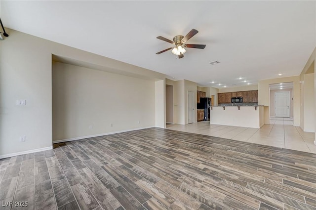 unfurnished living room featuring ceiling fan, baseboards, and light wood-type flooring