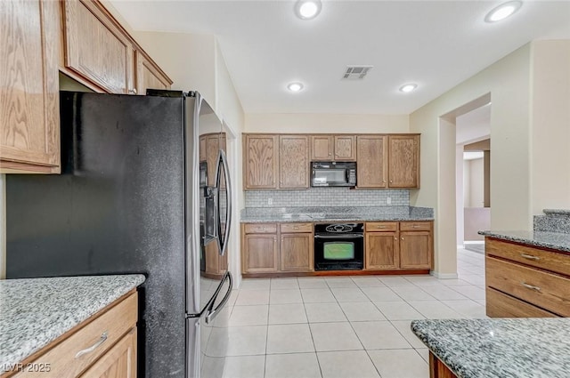 kitchen with visible vents, decorative backsplash, light stone counters, light tile patterned floors, and black appliances