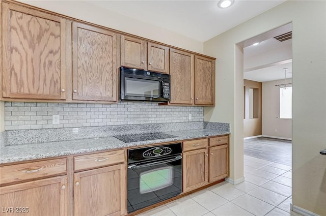 kitchen featuring decorative backsplash, light stone countertops, baseboards, light tile patterned floors, and black appliances