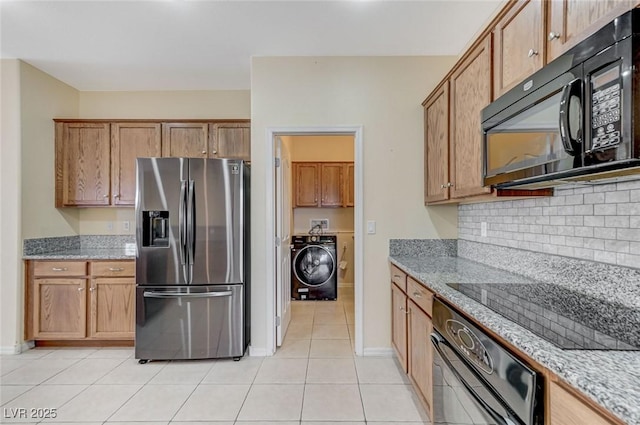 kitchen with washer / dryer, black appliances, light stone countertops, and tasteful backsplash
