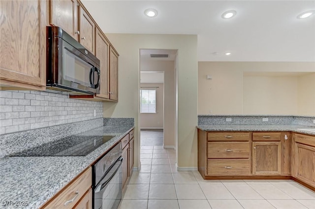 kitchen featuring visible vents, tasteful backsplash, light stone counters, light tile patterned floors, and black appliances