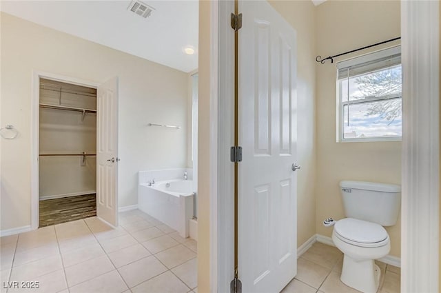 full bathroom featuring tile patterned flooring, toilet, baseboards, visible vents, and a garden tub