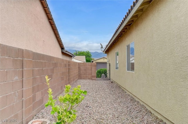 view of side of property with a fenced backyard and stucco siding