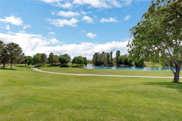 view of home's community with a water view, view of golf course, and a yard