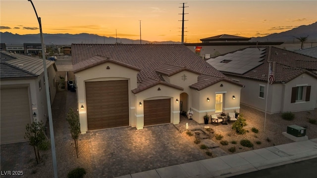 6325 Gambetta St, Las Vegas, NV 89115 - mediterranean / spanish house featuring a garage, stucco siding, a mountain view, decorative driveway, and a tiled roof