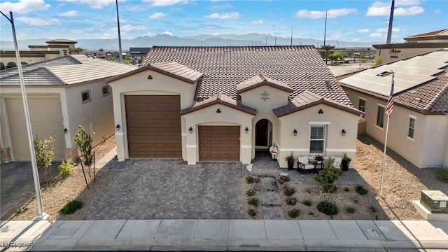 6325 Gambetta St, Las Vegas, NV 89115 - mediterranean / spanish-style home featuring a tile roof, a garage, stucco siding, a mountain view, and decorative driveway