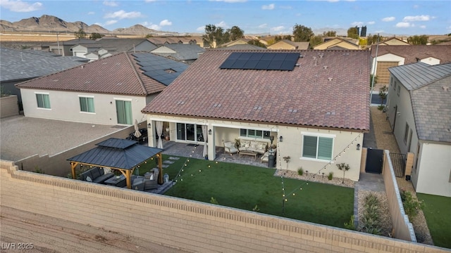 6325 Gambetta St, Las Vegas, NV 89115 - back of property featuring a gazebo, stucco siding, outdoor lounge area, roof mounted solar panels, and a fenced backyard