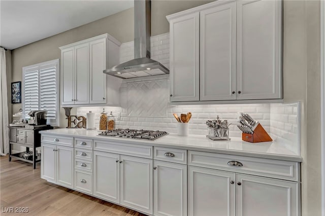 6325 Gambetta St, Las Vegas, NV 89115 - kitchen with light countertops, stainless steel gas stovetop, wall chimney exhaust hood, and tasteful backsplash
